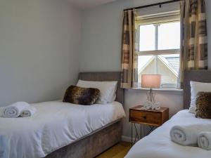 a bedroom with two twin beds and a window at Queens View Lodge in Inchmarlo