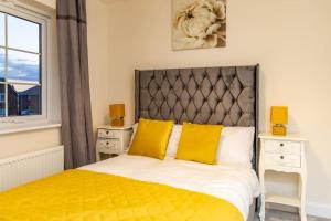 een slaapkamer met een bed met gele kussens en een raam bij Cozy 3 bed Sasha house in Beeston Nottingham in Nottingham