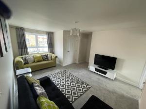 a living room with a couch and a flat screen tv at Cozy 3 bed Sasha house in Beeston Nottingham in Nottingham