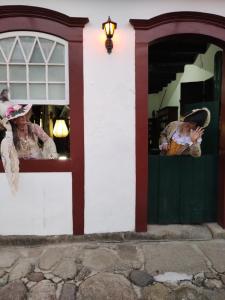 Dos mujeres disfrazadas parados en las ventanas de un edificio en Pousada Arte Colonial - Casarão Histórico do Séc XVIII, en Paraty