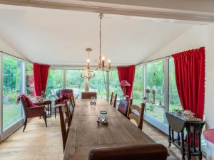 a dining room with a long table and red drapes at Beautiful holiday home in Baarle Nassau with garden in Baarle-Nassau