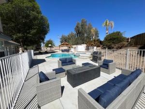 eine Terrasse mit Stühlen und einen Pool mit einem Zaun in der Unterkunft Kern River Home in Bakersfield