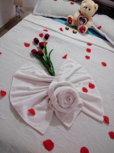 a white bed with red hearts and a teddy bear and flowers at Pousada Aconchego Recanto Canto Do Mar in Bairro da Enseada
