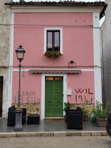 un bâtiment rose avec une porte verte et une fenêtre dans l'établissement Ancient Stone 'Casa Rosa'- Sea and Mountain View Tranquil Borgo, à Tavenna