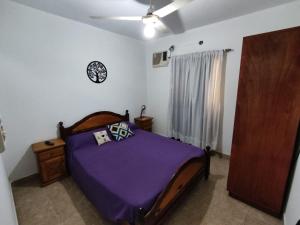 a bedroom with a bed with purple sheets and a ceiling at HUGO 1 in Colón