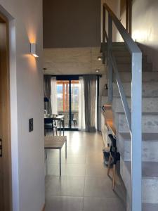 a living room with a staircase and a dining room at ENTREVERDES Departamentos in El Bolsón