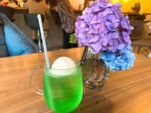 a green drink in a mug next to a vase of purple flowers at Hakuba Inn Bloom - Vacation STAY 95727 in Hakuba