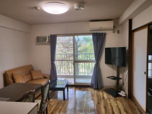 uma sala de estar com um sofá e uma grande janela em Hakuba Inn Bloom - Vacation STAY 95727 em Hakuba