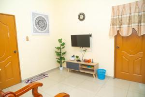 a living room with a tv and a door at Adorable 2-bedroom home with Wi-Fi, Netflix and BBQ grill in Rembau