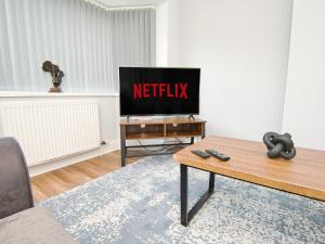 una sala de estar con TV con el cartel de netflix. en Cosy 3 bed with Parking- Family and Contractors, en Birmingham