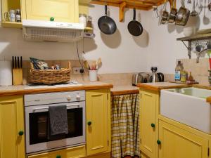 a kitchen with yellow cabinets and a sink at Church Cottage in Rigg