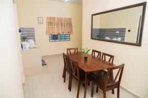 a dining room with a table and chairs and a mirror at Adorable 2-bedroom home with Wi-Fi, Netflix and BBQ grill in Rembau