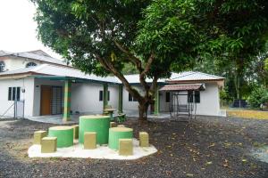 a building with a tree and a table and benches at Adorable 2-bedroom home with Wi-Fi, Netflix and BBQ grill in Rembau