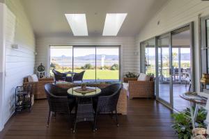 um alpendre coberto com uma mesa e cadeiras em The Matarangi B & B em Matarangi