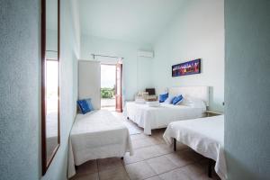 a hotel room with two beds and a window at Baja Azzurra in Bari Sardo