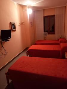 ein Hotelzimmer mit 3 Betten und einem TV in der Unterkunft Affittacamere Su Padru in Ittiri