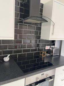 een keuken met zwarte en witte tegels op de muur bij 2 Bedroom House next to Slade Green Station in Slades Green