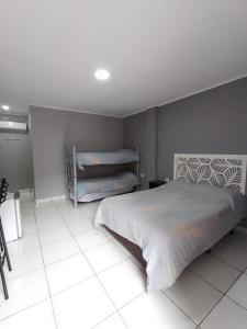 - une chambre avec un lit et du carrelage blanc dans l'établissement Kuri Hospedaje Turístico, à Puerto Iguazú