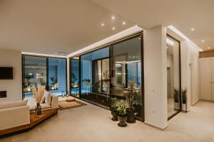 una sala de estar con grandes ventanas de cristal y un sofá. en Saphira Villa, en Katávolos