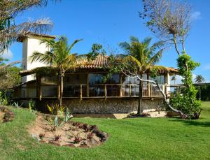 ein Haus mit einer umlaufenden Veranda mit Palmen in der Unterkunft Grimms Pousada de Contos in Porto de Sauipe
