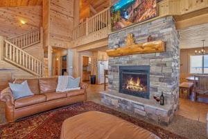 a living room with a large stone fireplace at Liberty Lodge by KABINO Hot Tub Air Hockey 3 Living Rooms 7 bedrooms Boat Launch Reservoir ATV Snowmobile Trails WiFi in Island Park