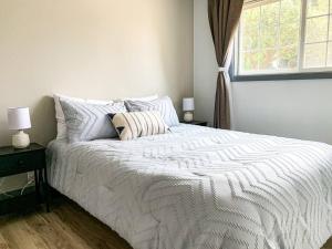 a white bed in a bedroom with a window at Riverwalk Retreat: Spacious, Hot tub, near Autzen in Springfield