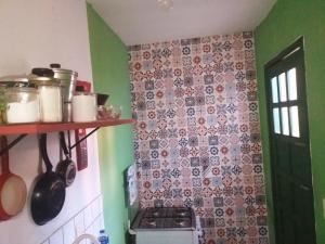 a kitchen with a stove and a tile wall at Casa Relva in Lençóis