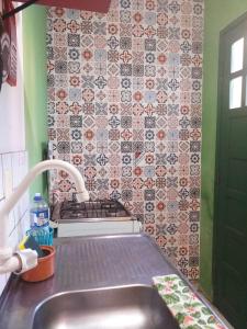 a kitchen with a sink and a tile wall at Casa Relva in Lençóis