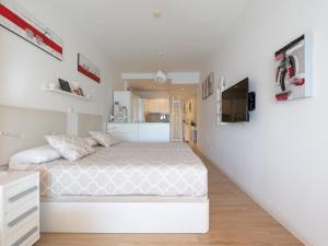 a white bedroom with a bed and a kitchen at Attico Albareda in Las Palmas de Gran Canaria