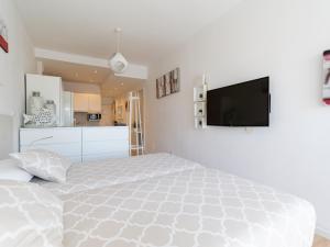 a white bedroom with a bed and a flat screen tv at Attico Albareda in Las Palmas de Gran Canaria