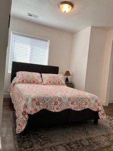 a bedroom with a bed with a red comforter and a window at Perfect Little Place in Tooele