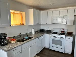 a kitchen with white cabinets and a white stove top oven at Perfect Little Place in Tooele