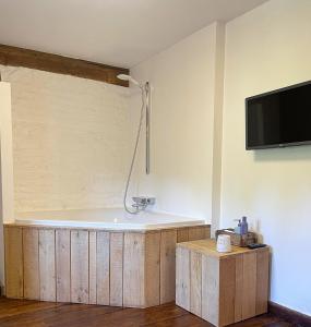 a bathroom with a bath tub with a tv on the wall at Hoeve Berghof in Heerlen