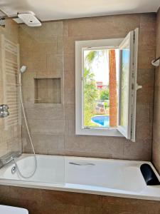 a bathroom with a bath tub with a window at Cheerful Townhouse Center Sitges 5 bedrooms Pool and Terrace in Sitges