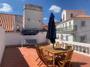 een patio met een tafel en een parasol op een dak bij Império House in Santiago do Cacém