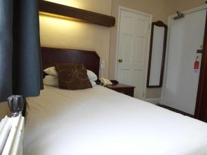 a bedroom with a large white bed with brown pillows at Best Western The George Hotel, Swaffham in Swaffham
