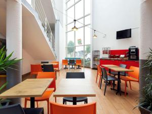 um restaurante com mesas de madeira e cadeiras laranja em Hôtel F1 Reims Tinqueux em Reims