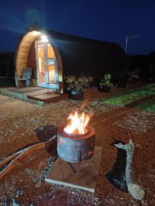 a fire pit in front of a cabin at night at Nesswood Luxury Glamping in Derry Londonderry