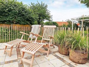 dwa drewniane krzesła siedzące na patio obok roślin w obiekcie 4 person holiday home in S by w mieście Sæby