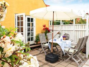stół i krzesła pod parasolem na patio w obiekcie 4 person holiday home in S by w mieście Sæby