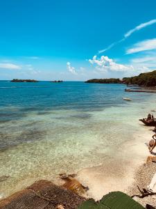una playa con agua clara e islas al fondo en Eco Hotel Las Palmeras, en Isla Grande