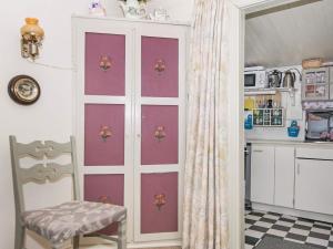 Lakolkにある4 person holiday home in R mのピンクのドアと椅子付きのキッチン