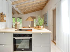 uma cozinha com armários brancos e um forno preto em 6 person holiday home in Gr sted em Græsted
