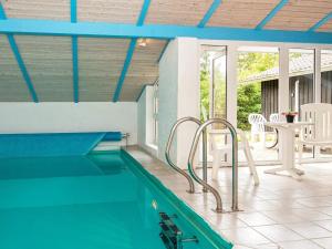 a swimming pool in a house with a blue ceiling at Holiday home Henne CXXVII in Henne Strand