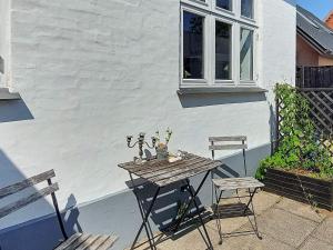 6 person holiday home in Frederikshavn في فريكشهاون: طاولة خشبية وكرسيين على الفناء