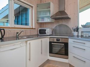 La cuisine est équipée de placards blancs, d'un évier et d'un four micro-ondes. dans l'établissement 6 person holiday home in Tarm, à Tarm