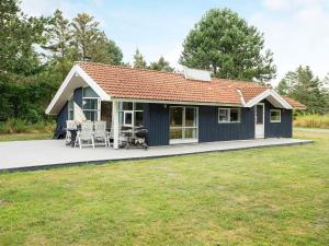 a blue cottage with a deck and lawn at Three-Bedroom Holiday home in Rødby 6 in Kramnitse