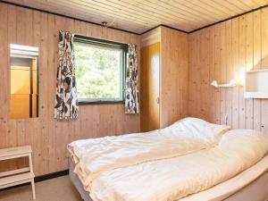 ブラーバンドにあるHoliday home Blåvand XXIIIの木製の壁に大きなベッドが備わるベッドルーム1室