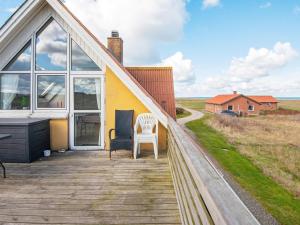 a house with a deck with a white chair on it at 12 person holiday home in Lemvig in Ferring