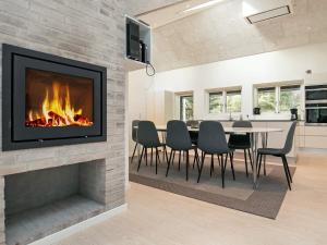 a fireplace in a living room with a table and chairs at 14 person holiday home in L kken in Løkken